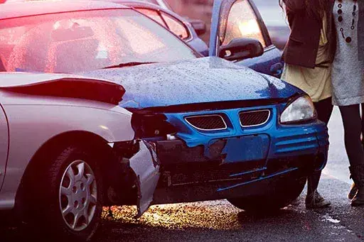 Two vehicles after a front-end collision on a wet road